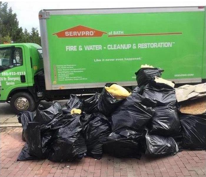 Image of SERVPRO's green truck, and waste bags on floor.